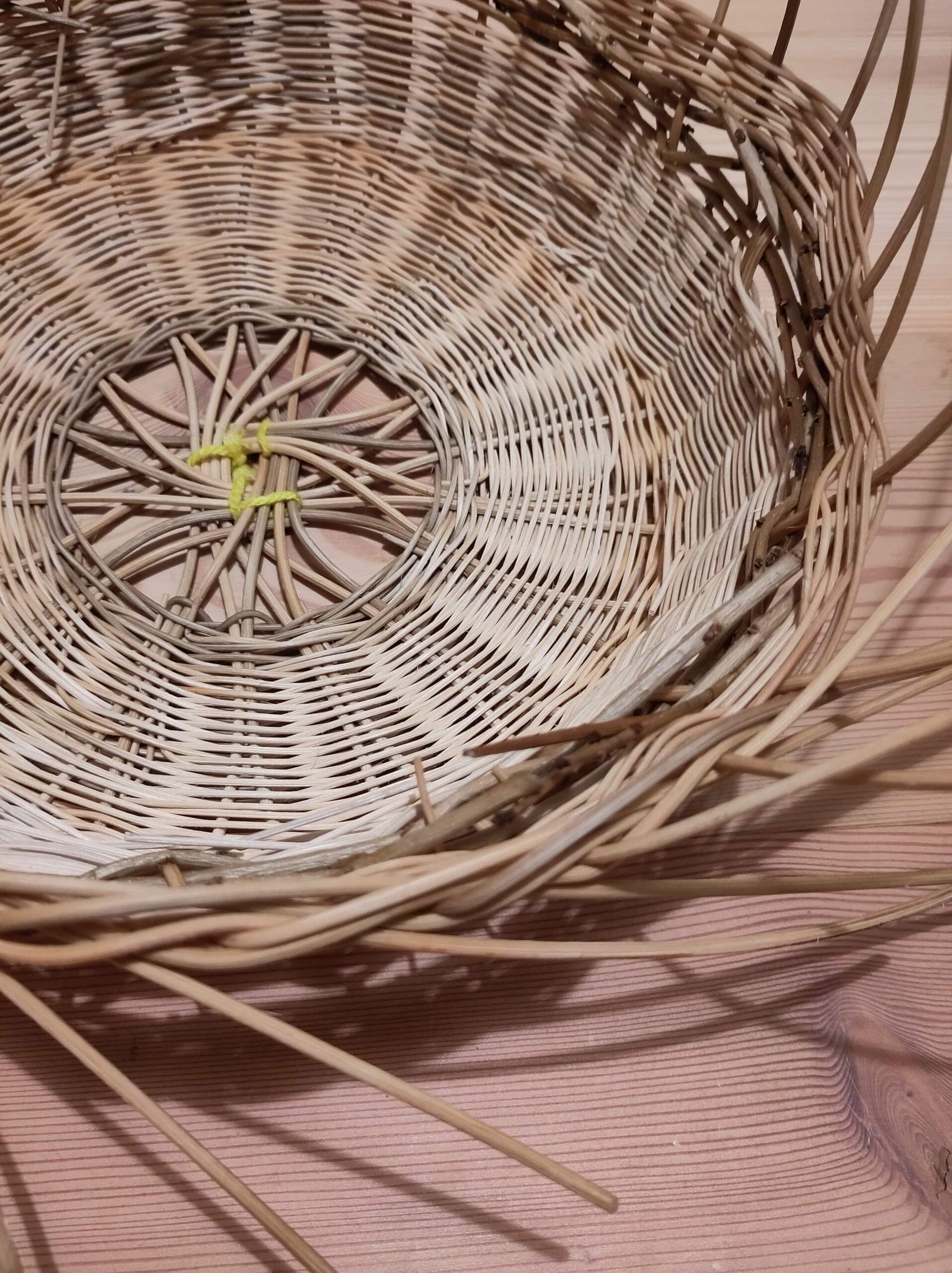 Runder Korb aus geflochtenem Weidenholz auf Holzboden